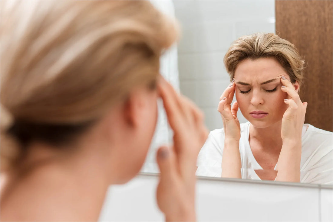 Woman with a headache looking in the mirror